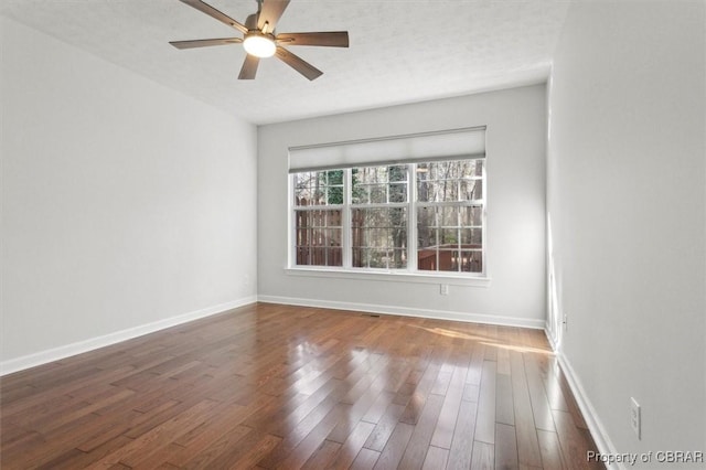 spare room with a ceiling fan, wood finished floors, baseboards, and a textured ceiling