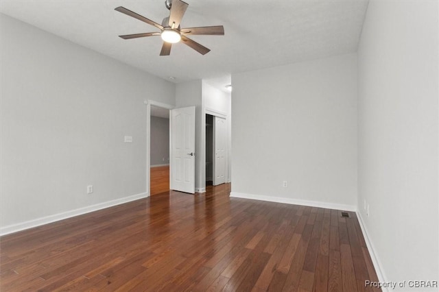 spare room featuring baseboards, dark wood finished floors, and a ceiling fan