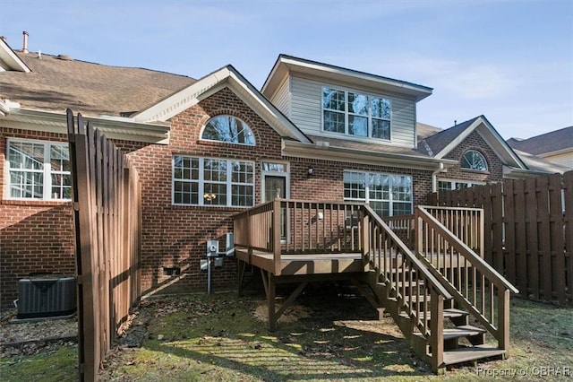 back of property with brick siding, central air condition unit, a wooden deck, and fence