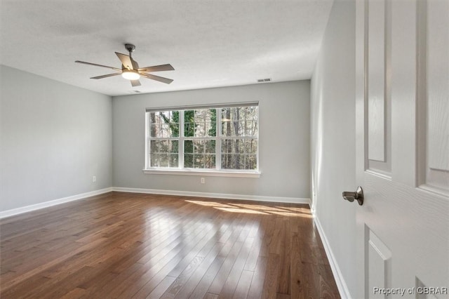 empty room featuring hardwood / wood-style flooring, a ceiling fan, baseboards, and visible vents