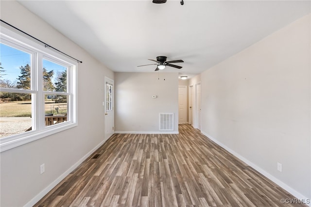 spare room with visible vents, ceiling fan, baseboards, and wood finished floors