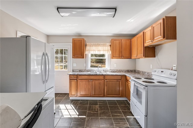 kitchen with white appliances, brown cabinetry, light countertops, and a sink