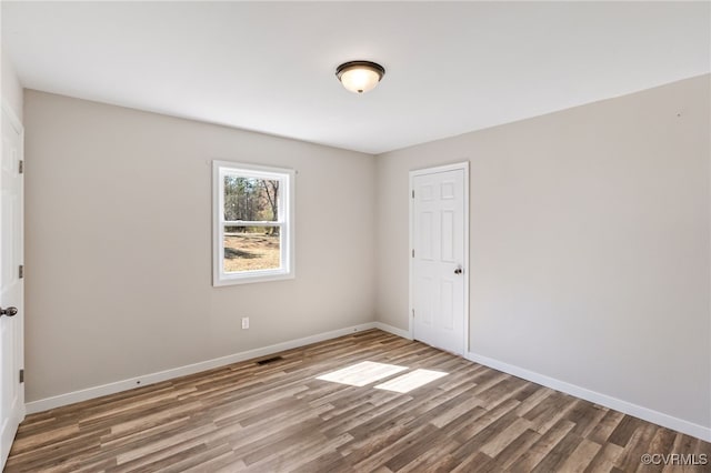 unfurnished room featuring visible vents, baseboards, and wood finished floors