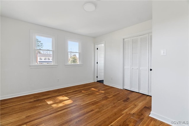 unfurnished bedroom featuring a closet, baseboards, and wood finished floors