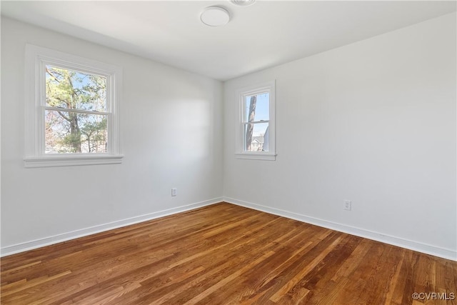 spare room with baseboards, a healthy amount of sunlight, and wood finished floors