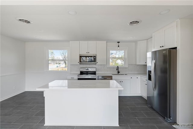 kitchen featuring a sink, stainless steel appliances, backsplash, and visible vents