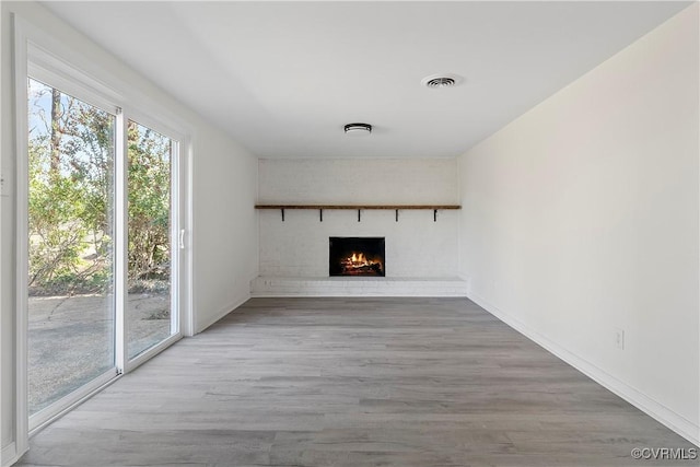 unfurnished living room featuring visible vents, baseboards, wood finished floors, and a fireplace