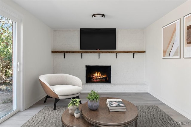 sitting room featuring wood finished floors, a fireplace, and baseboards