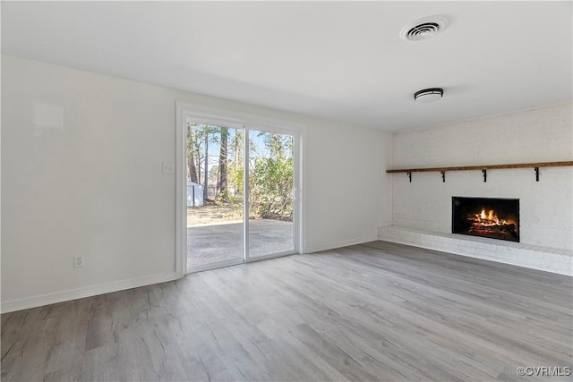 unfurnished living room with visible vents, baseboards, wood finished floors, and a fireplace