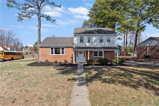 view of front facade with brick siding, a chimney, and a front yard