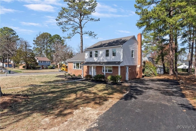 view of front of property with brick siding, driveway, and a chimney