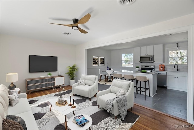 living area with dark wood-type flooring, visible vents, and a wealth of natural light