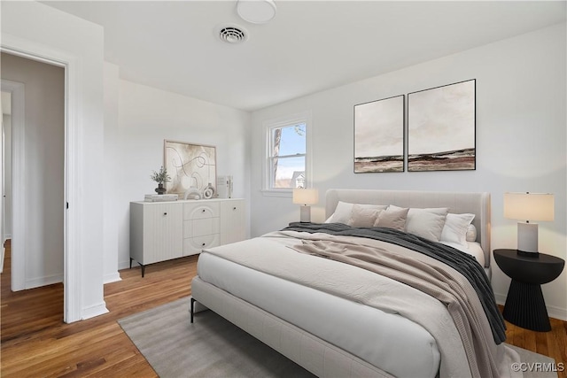 bedroom with visible vents, baseboards, and wood finished floors