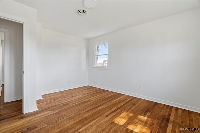 empty room with visible vents, baseboards, and wood finished floors