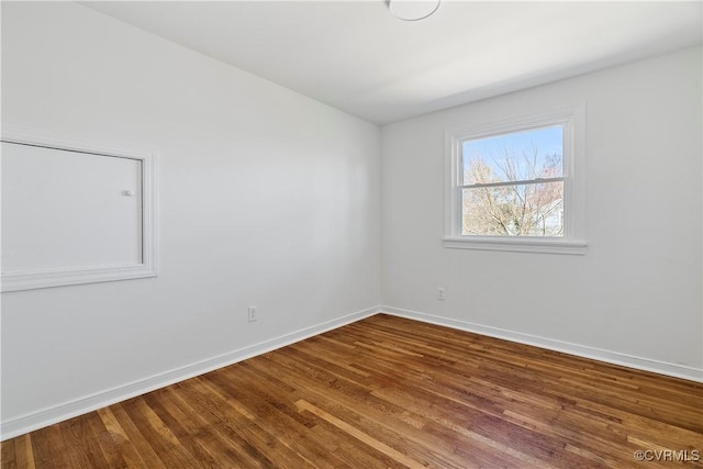 spare room with baseboards and wood finished floors