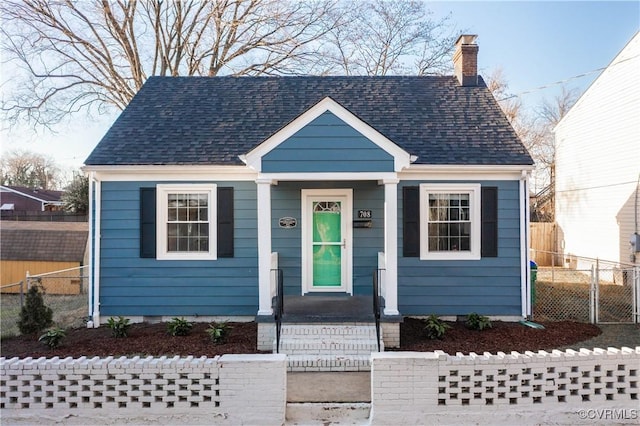 bungalow-style house featuring crawl space, a chimney, roof with shingles, and fence