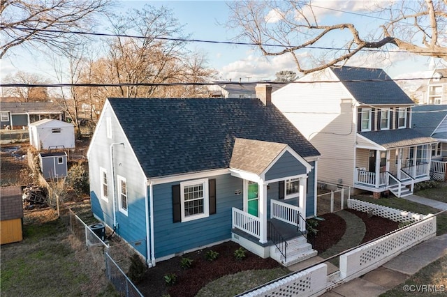 view of front of home featuring a shingled roof, fence, central air condition unit, covered porch, and a chimney