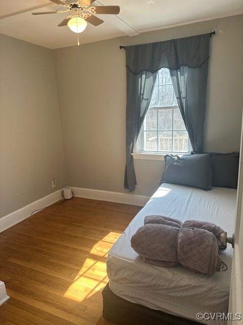 bedroom featuring a ceiling fan, baseboards, and wood finished floors