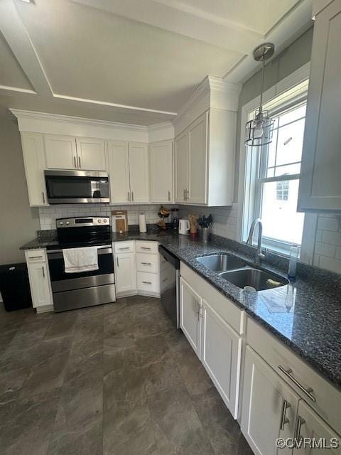 kitchen featuring backsplash, dark stone countertops, white cabinets, stainless steel appliances, and a sink