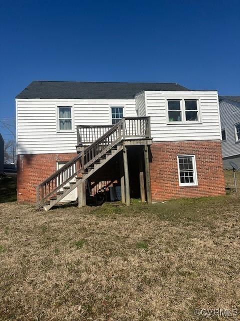 rear view of property with stairway, brick siding, a wooden deck, and a lawn