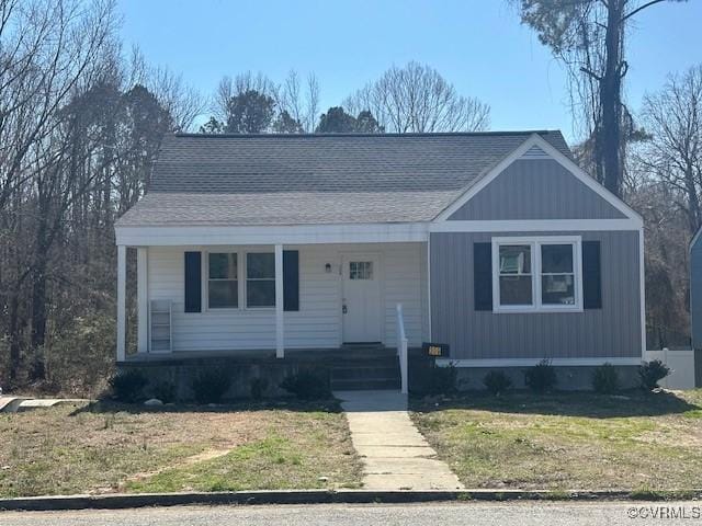 view of front of home with covered porch, a front yard, and roof with shingles