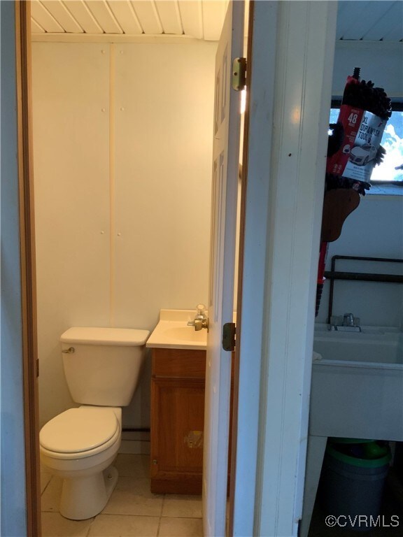 half bathroom featuring tile patterned floors, toilet, and vanity