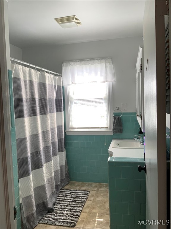 bathroom with tile patterned floors, visible vents, a shower with shower curtain, and a sink