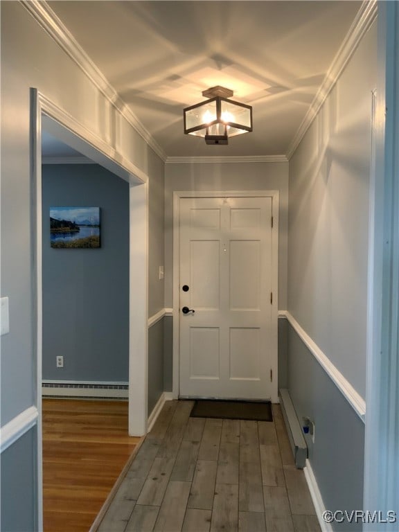 doorway to outside featuring wood finished floors, baseboard heating, and ornamental molding