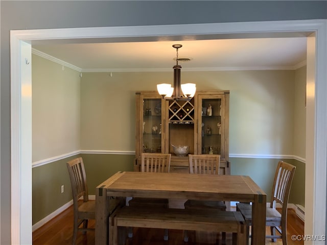 dining room featuring an inviting chandelier, crown molding, wood finished floors, and baseboards