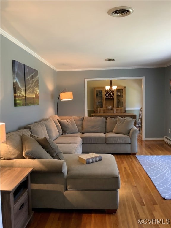 living room featuring visible vents, wood finished floors, baseboards, and ornamental molding