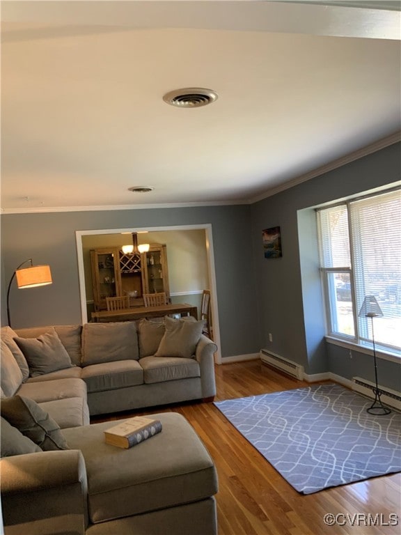 living room featuring a baseboard heating unit, crown molding, wood finished floors, and baseboards