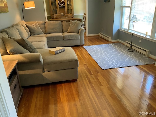 unfurnished living room featuring a baseboard heating unit, baseboards, and wood finished floors