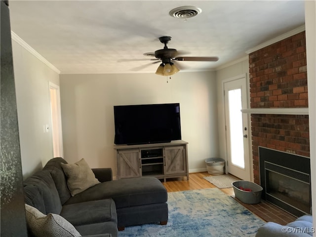 living room featuring a fireplace, crown molding, wood finished floors, and visible vents