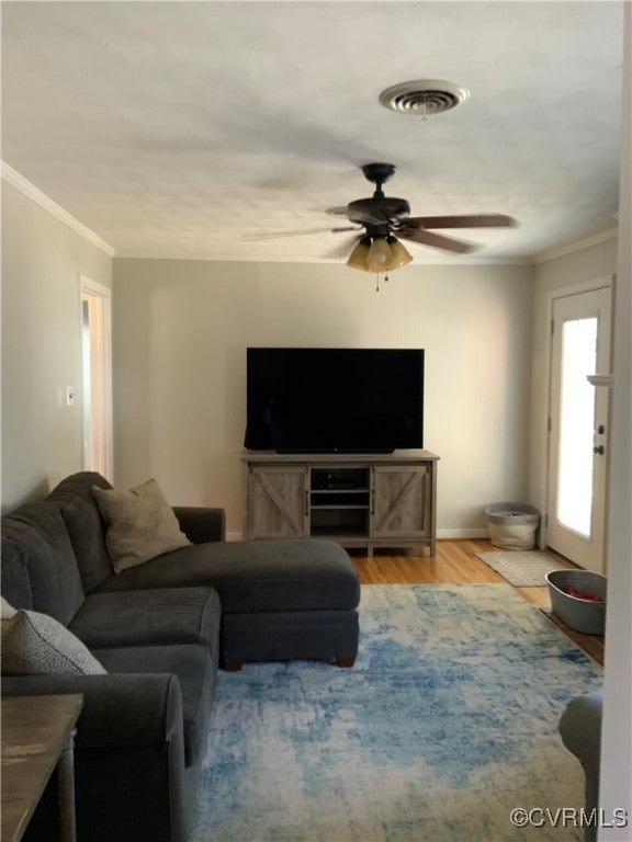 living area with visible vents, wood finished floors, ceiling fan, and ornamental molding