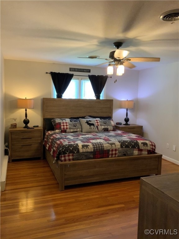 bedroom with visible vents, a ceiling fan, and wood finished floors