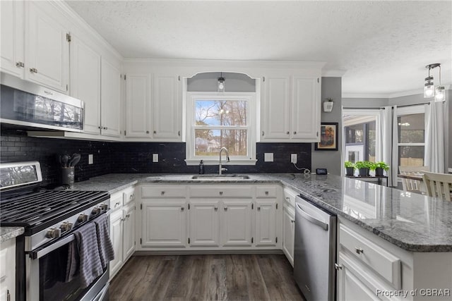 kitchen featuring a sink, dark wood finished floors, white cabinetry, appliances with stainless steel finishes, and a peninsula