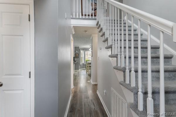 corridor featuring visible vents, baseboards, wood finished floors, and stairs