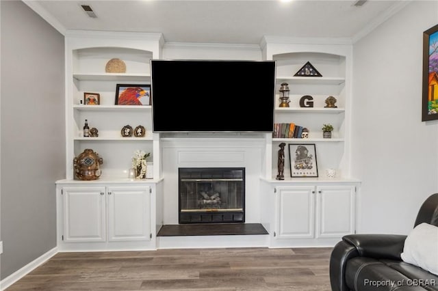 living room with built in features, visible vents, and wood finished floors