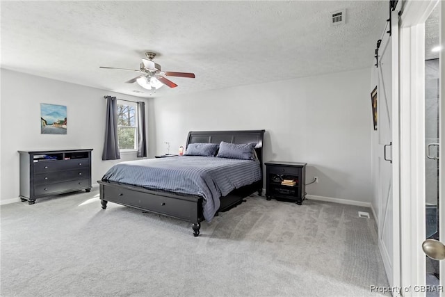 bedroom featuring visible vents, a textured ceiling, a barn door, and carpet floors