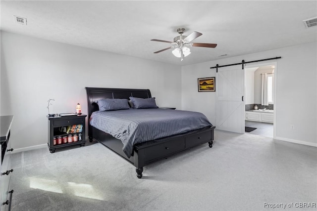 bedroom featuring visible vents, baseboards, ensuite bathroom, and a barn door