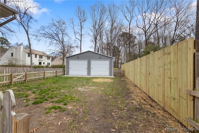 view of yard featuring a fenced backyard, a detached garage, and an outdoor structure