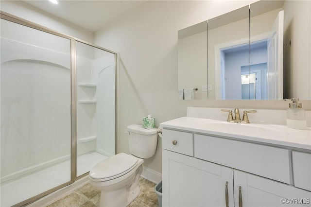 bathroom with vanity, toilet, baseboards, and a stall shower