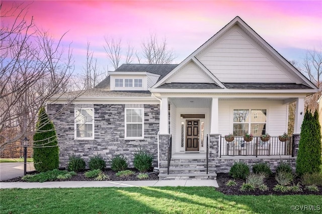 view of front of house featuring a porch, stone siding, and a front lawn