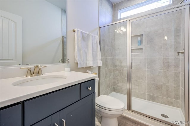 full bathroom with wood finished floors, toilet, a stall shower, and vanity