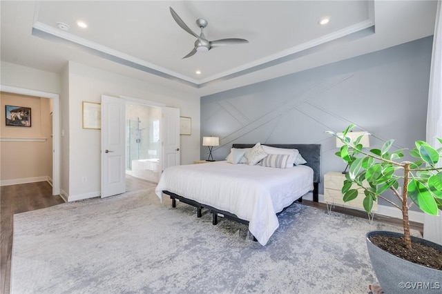 bedroom with recessed lighting, a tray ceiling, baseboards, and wood finished floors