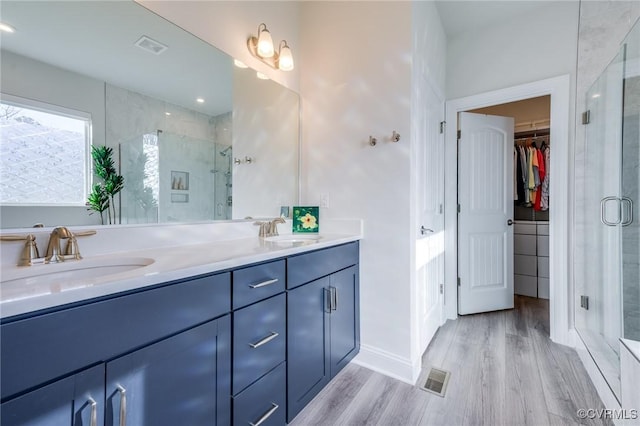 bathroom with a sink, wood finished floors, and a shower stall