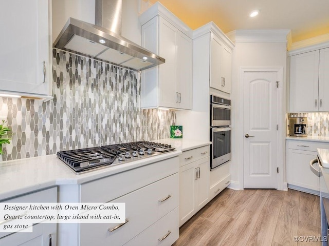 kitchen featuring appliances with stainless steel finishes, ornamental molding, light countertops, and wall chimney range hood