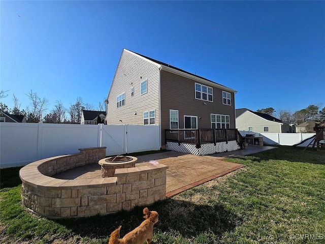 back of house featuring a gate, a fenced backyard, a fire pit, a patio area, and a lawn