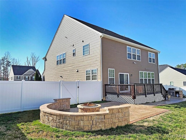 rear view of property with a gate, a wooden deck, a fenced backyard, a fire pit, and a patio area