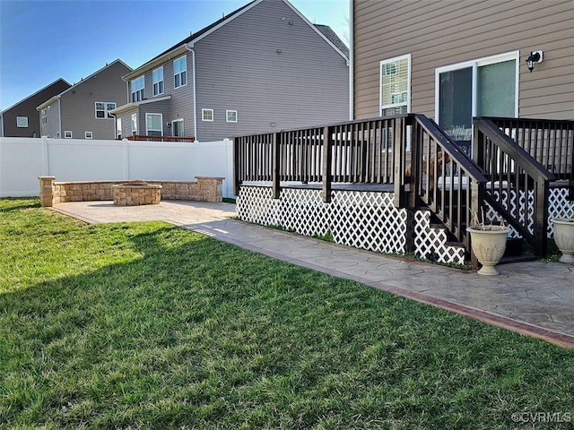 exterior space with a fire pit, fence, a lawn, a deck, and a patio area